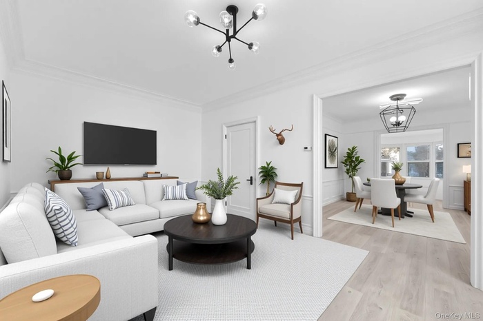 Living area with a chandelier, light wood-style flooring, and crown molding