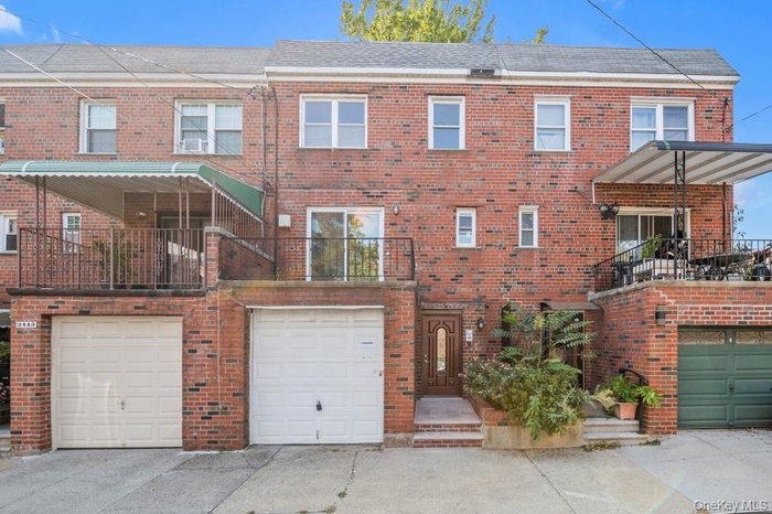 Traditional home with a balcony, brick siding, driveway, and a garage