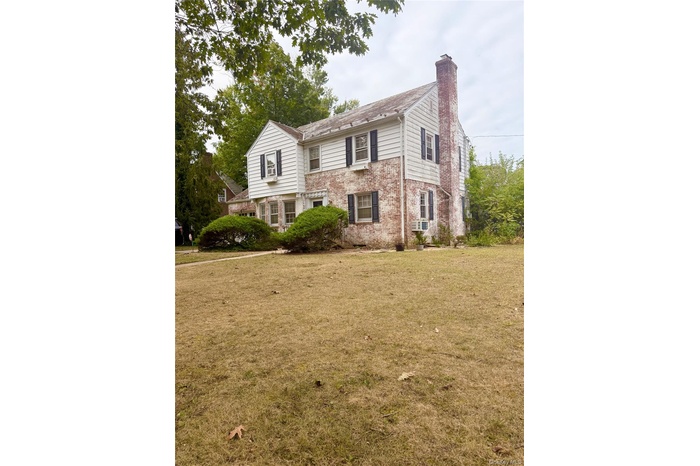 View of front facade with a chimney, a front lawn, and brick siding