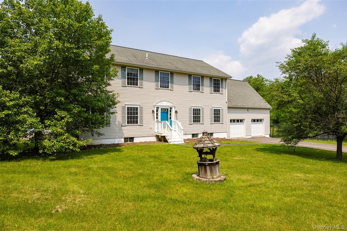 Colonial home featuring a front lawn and an attached garage