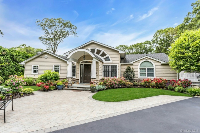 View of front of home with a front yard, roof with shingles, and stone siding