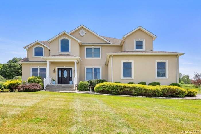 View of front facade with stucco siding and a front yard