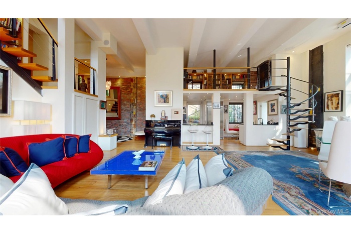 Living area with stairway, a high ceiling, wood finished floors, and brick wall