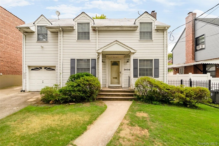 View of front of home featuring a chimney, driveway, and an attached garage