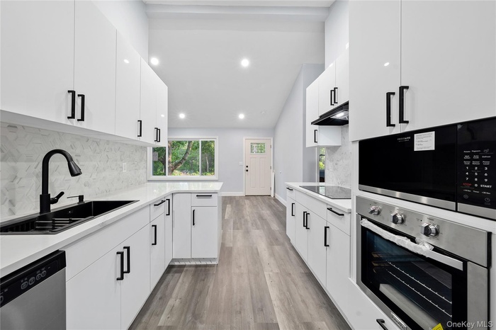 Kitchen featuring stainless steel appliances, a sink, light countertops, and recessed lighting
