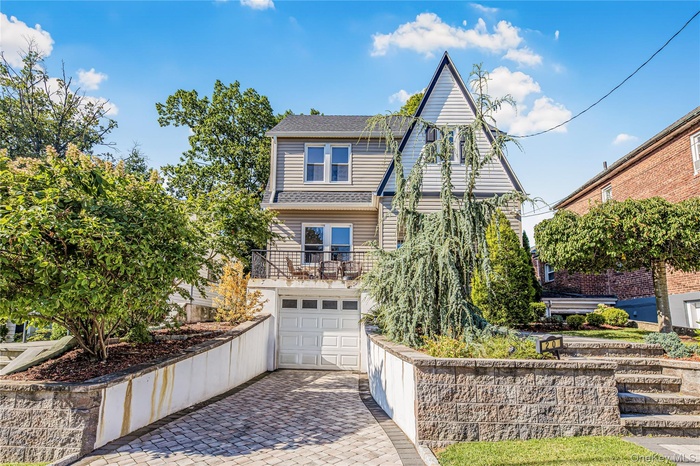 View of front of property featuring decorative driveway, a garage, a balcony, and roof with shingles