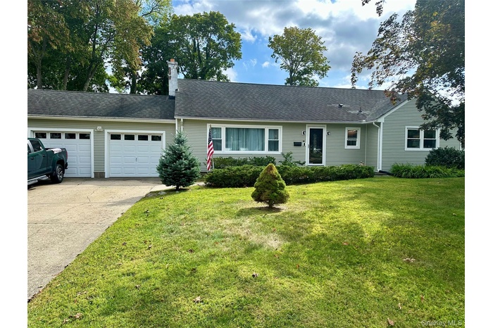 Ranch-style house featuring concrete driveway, a garage, roof with shingles, and a front lawn
