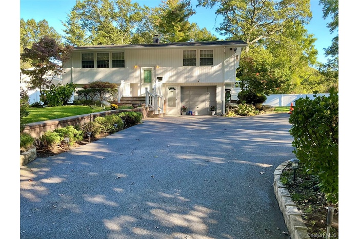 Raised ranch with asphalt driveway and a garage