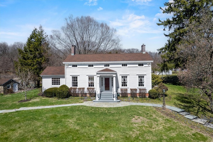 View of front facade featuring a chimney and a front lawn