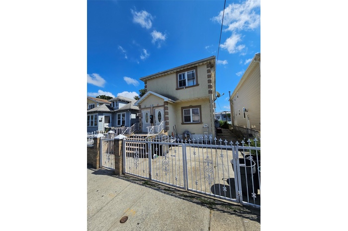 View of front of home with stucco siding, a fenced front yard, and a gate