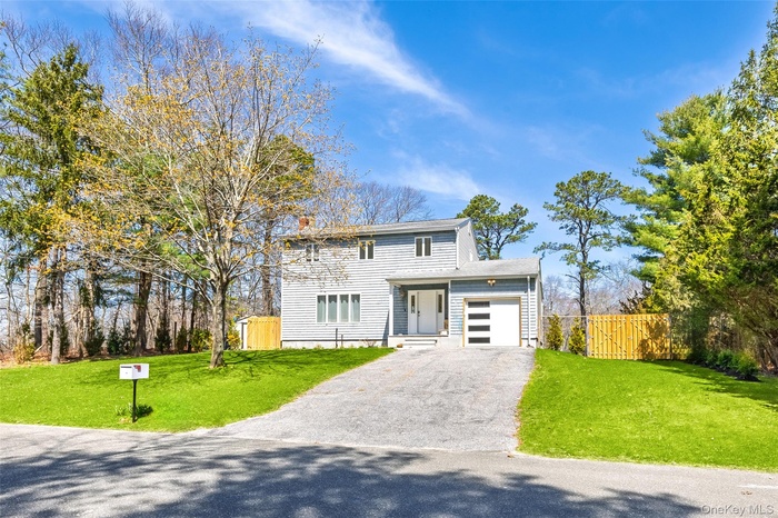 View of front of house with an attached garage, driveway, and a gate