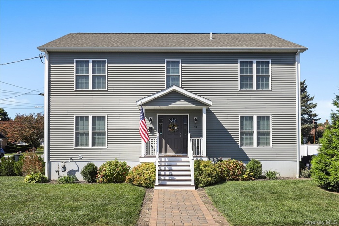 View of front of house with a front lawn and roof with shingles