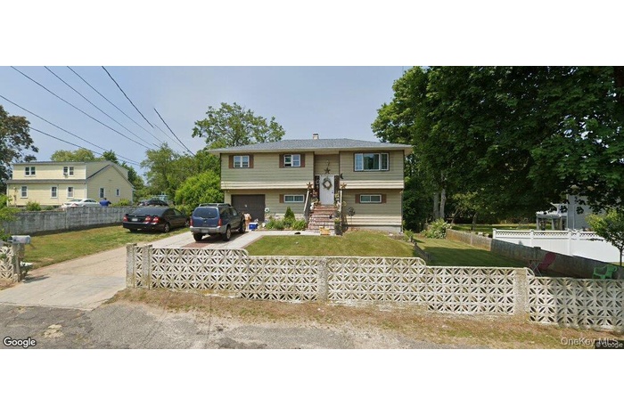 Raised ranch featuring concrete driveway, a fenced front yard, and a chimney