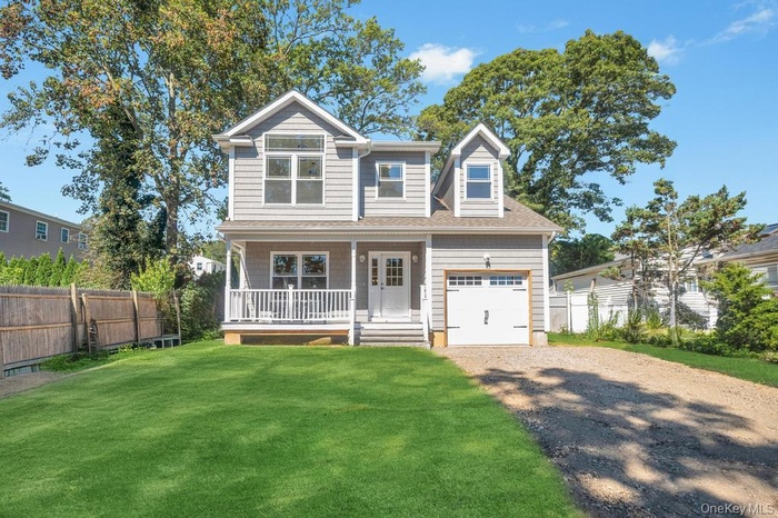 View of front of home featuring covered porch, driveway, and a garage. Grass virtually added to image.