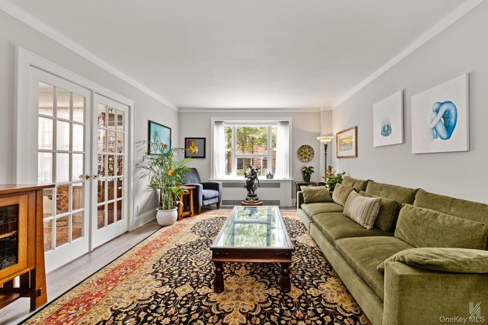 Living room with french doors, wood finished floors, and crown molding