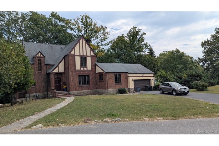 View of front of property with brick siding, a front yard, and asphalt driveway