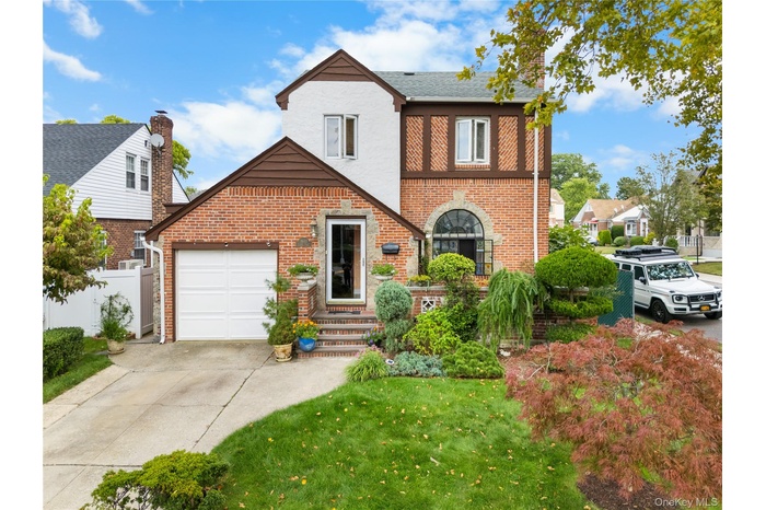 English style home with driveway, brick siding, and an attached garage