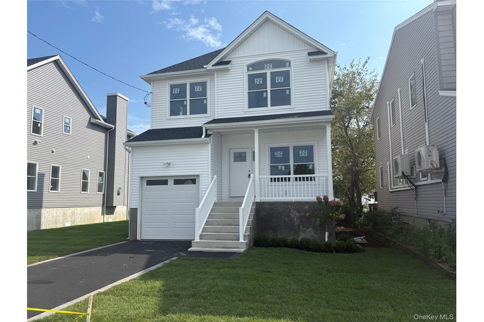 View of front of home with asphalt driveway, covered porch, a front yard, and a garage