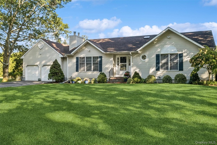 Single story home with asphalt driveway, a front lawn, a garage, a chimney, and a shingled roof
