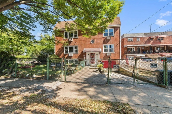 View of front facade featuring a gate, a fenced front yard, and brick siding
