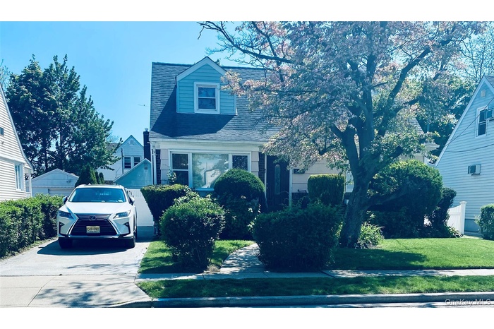View of front facade with a front yard and a shingled roof