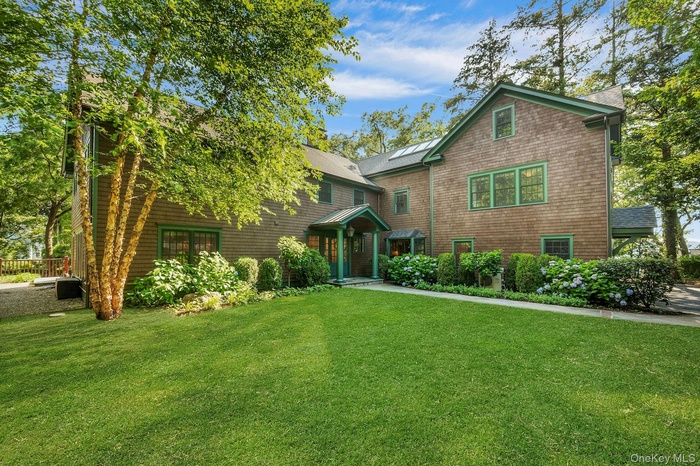 Shingle-style home featuring a front yard and a standing seam roof