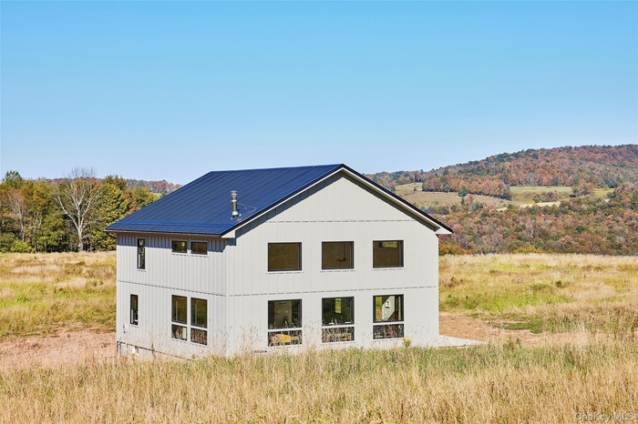 Rear view of house featuring board and batten siding and a view of trees