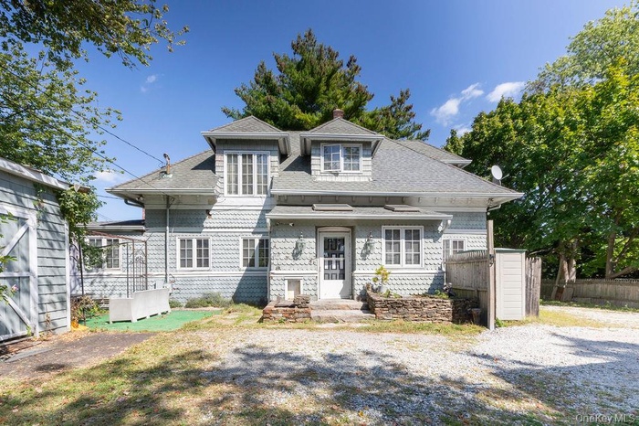 View of front of home with a shingled roof and a chimney