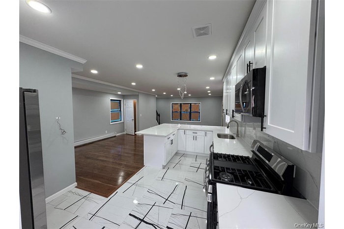 Kitchen with stainless steel appliances, recessed lighting, light stone countertops, white cabinets, and open floor plan