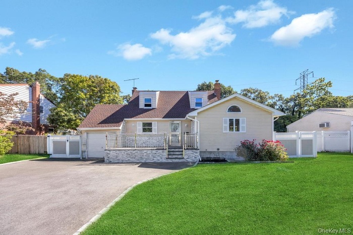 View of front facade featuring driveway, a chimney, and a gate