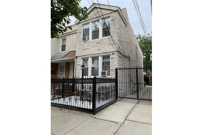 View of front facade featuring stone siding, a fenced front yard, a gate, and cooling unit