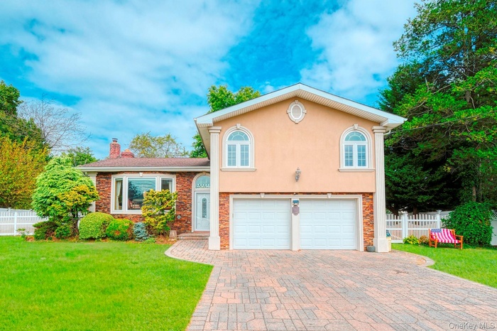 View of front of property featuring stucco siding, an attached garage, decorative driveway, stone siding, and a chimney