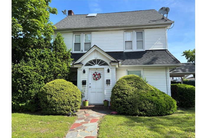 View of front of property with a shingled roof, a chimney, and a front lawn