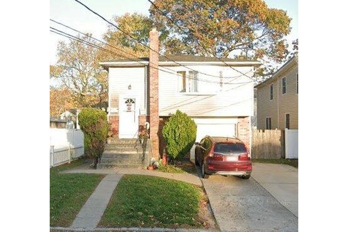 View of front facade featuring a carport, concrete driveway, and fence