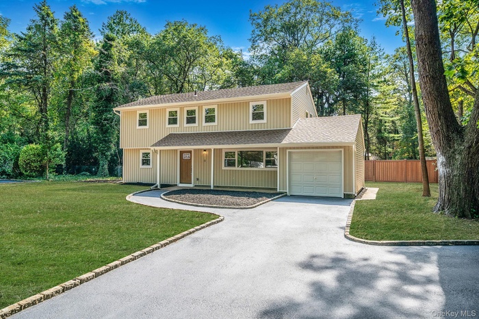 View of front of house with a shingled roof, driveway, an attached garage, and covered porch