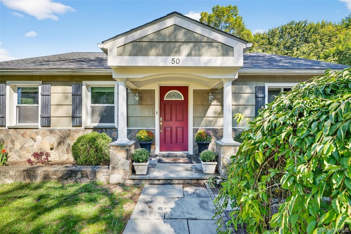 Entrance to property featuring stone siding, a shingled roof, and a porch