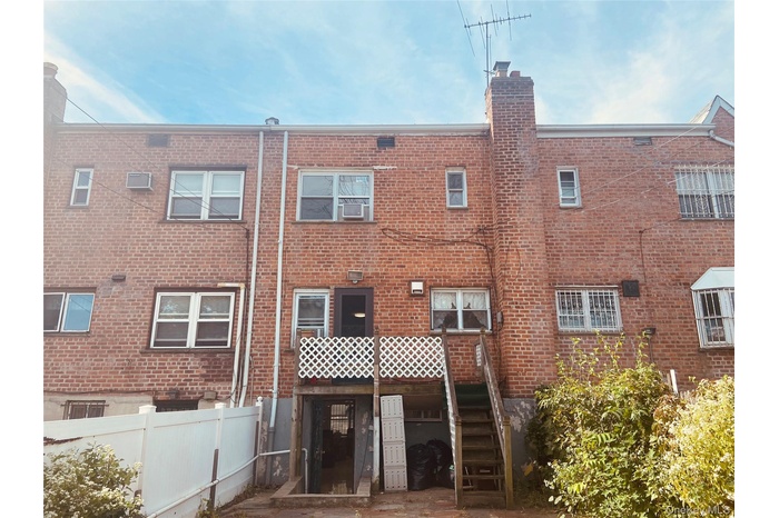 Rear view of property featuring brick siding, a chimney, a deck, and a patio area