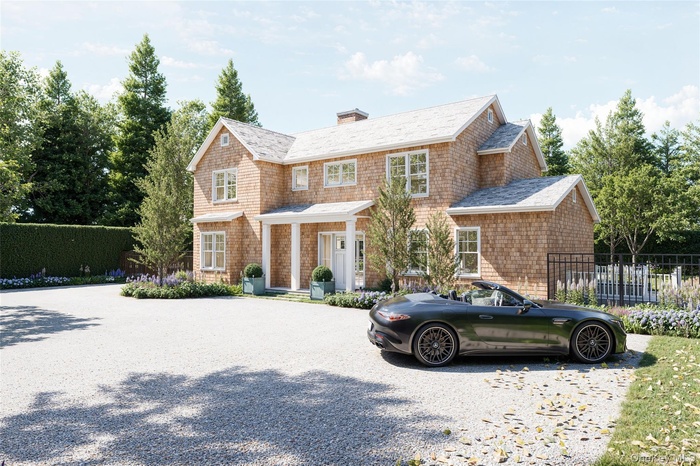 Shingle-style home featuring a chimney, a porch, and gravel driveway