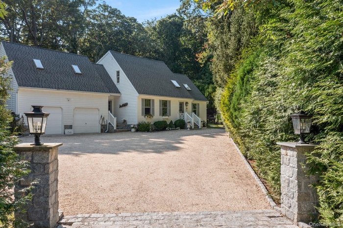 View of front facade featuring driveway, a shingled roof, and a garage