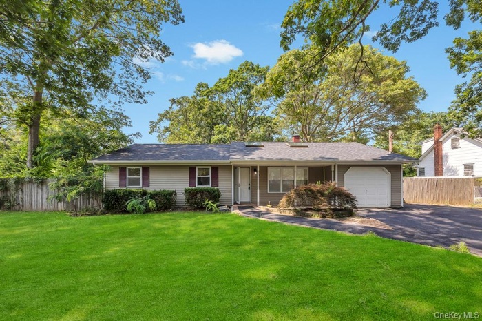 Single story home with an attached garage, driveway, and a chimney