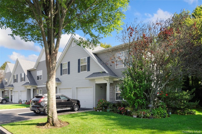 View of front of home featuring driveway, a front lawn, roof with shingles, and an attached garage
