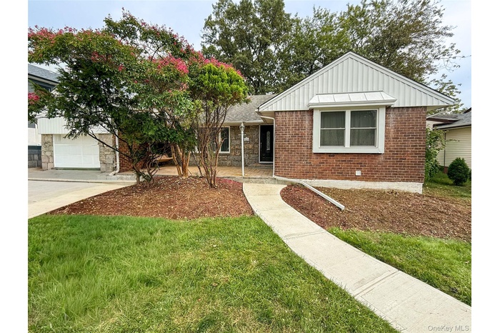 View of front facade with board and batten siding, a front lawn, stone siding, concrete driveway, and a garage
