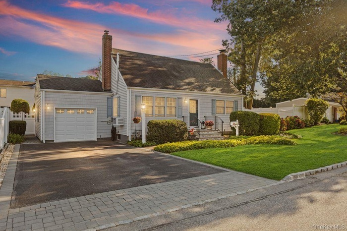 View of front of property featuring decorative driveway, an attached garage, and a chimney