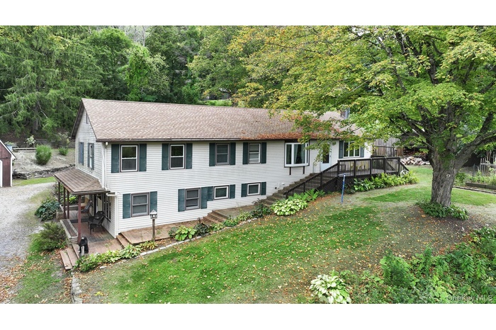 View of front of house featuring a front lawn, roof with shingles, and a deck