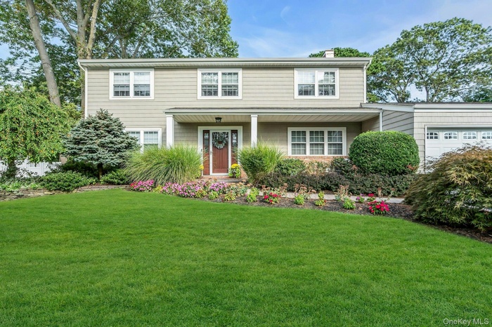 Traditional home featuring a front yard, a garage, a chimney, and covered porch