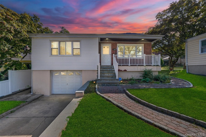 Ranch-style home featuring driveway, a lawn, a garage, stairway, and covered porch
