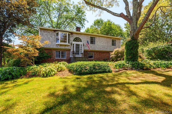 Split foyer home featuring a chimney, brick siding, and a front yard