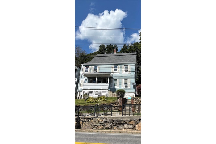 View of front of property featuring a fenced front yard, a chimney, and roof with shingles