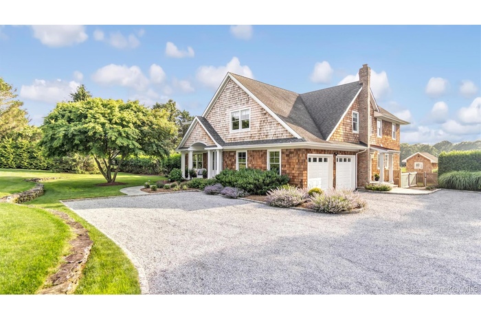 View of front of home with driveway, roof with shingles, an attached garage, and a chimney