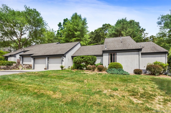 Mid-century modern home with roof with shingles, a garage, asphalt driveway, and a front lawn